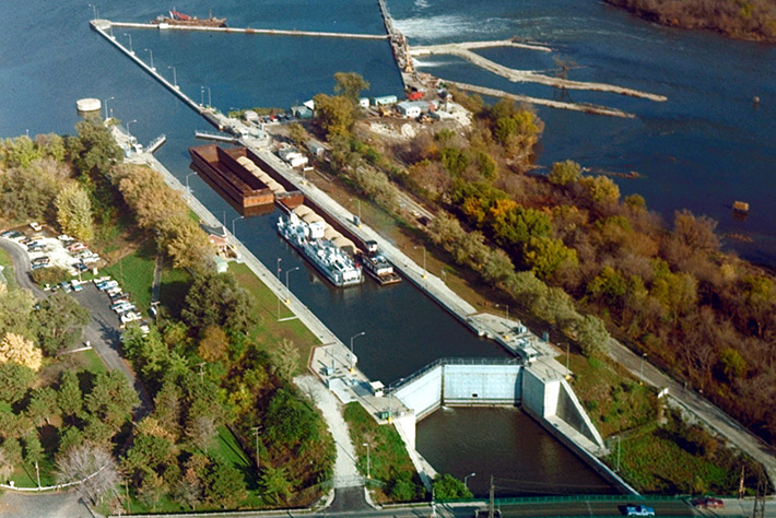 Overhead view of barges waiting in a lock along a river.